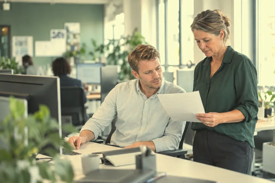 An in-house recruiter and a hiring manager review a short printed list together.